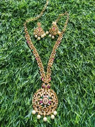 చెవి రింగులతో ఎర్రటి రాళ్ల గొలుసుతో నెమలి లేదా పూల డిజైన్. యొక్క చిత్రం